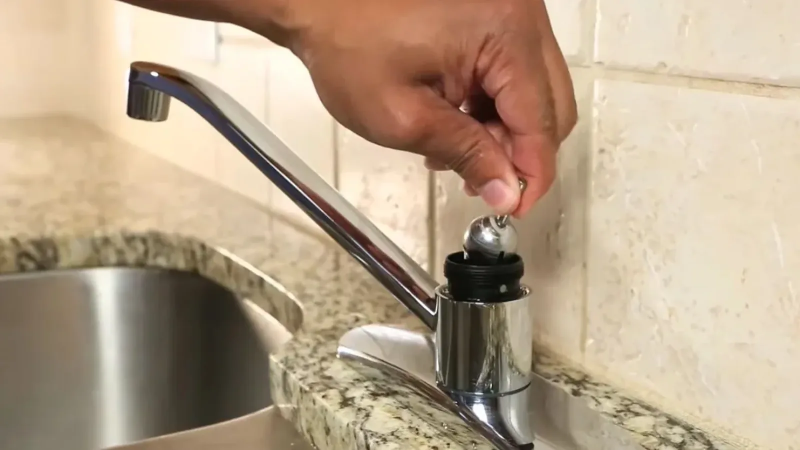 Hand removing the cartridge from a kitchen faucet
